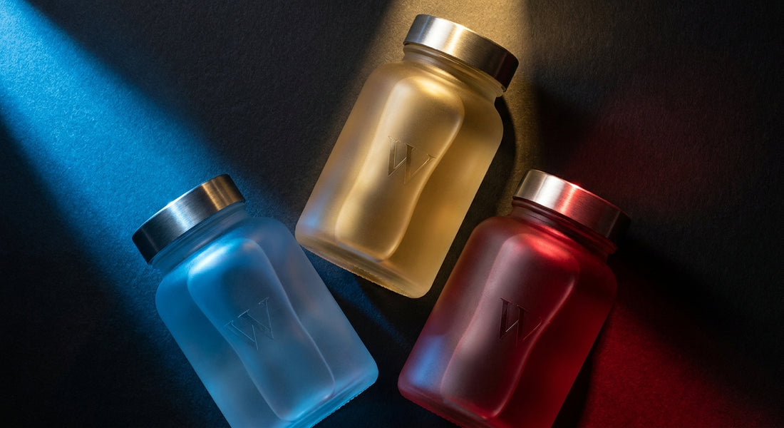 Three supplement bottles illuminated in blue, gold, and red lighting arranged against a dark background, symbolizing distinct vitality formula choices for men.